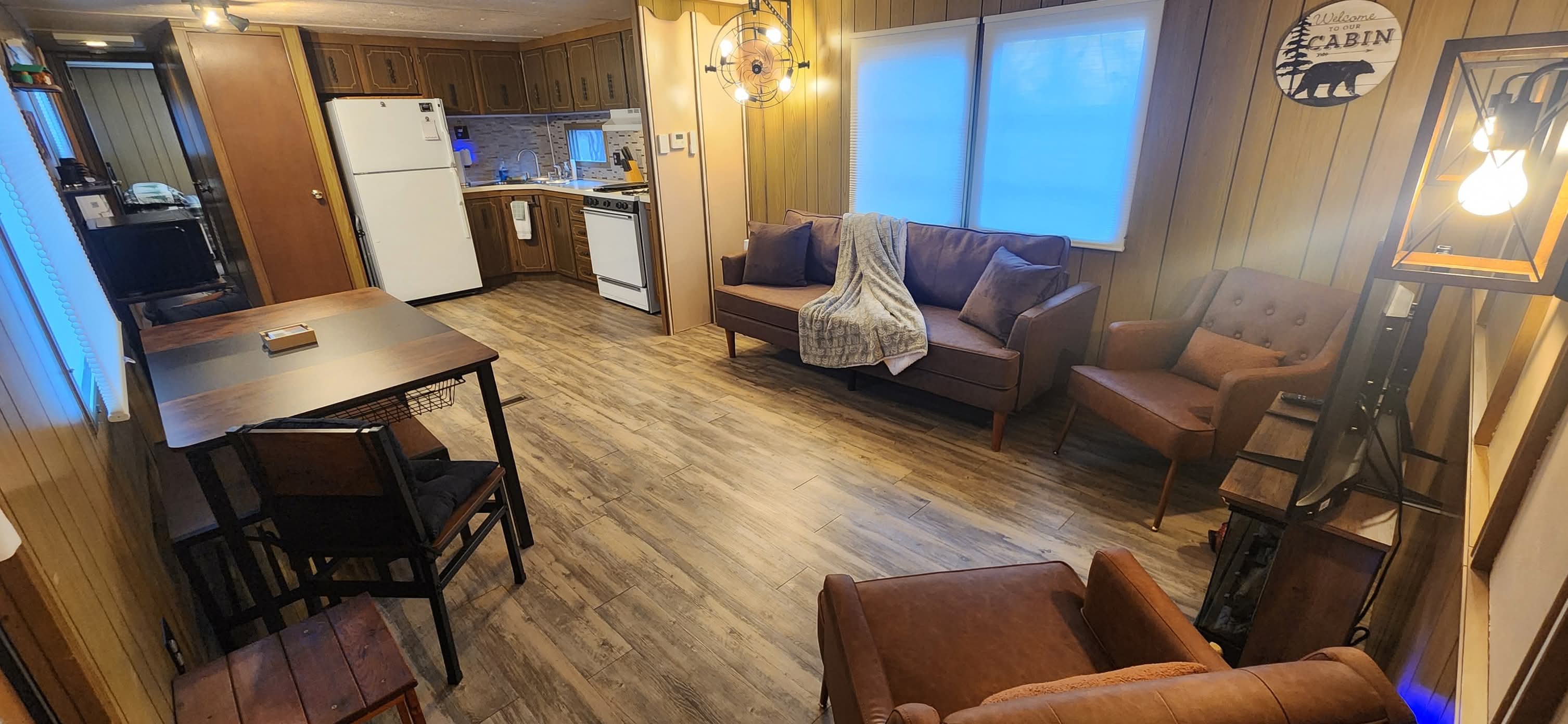 Functional kitchen equipped with electric stove, refrigerator, wood cabinetry, and ample countertop workspace, designed for practical meal preparation in a cozy rustic cabin setting